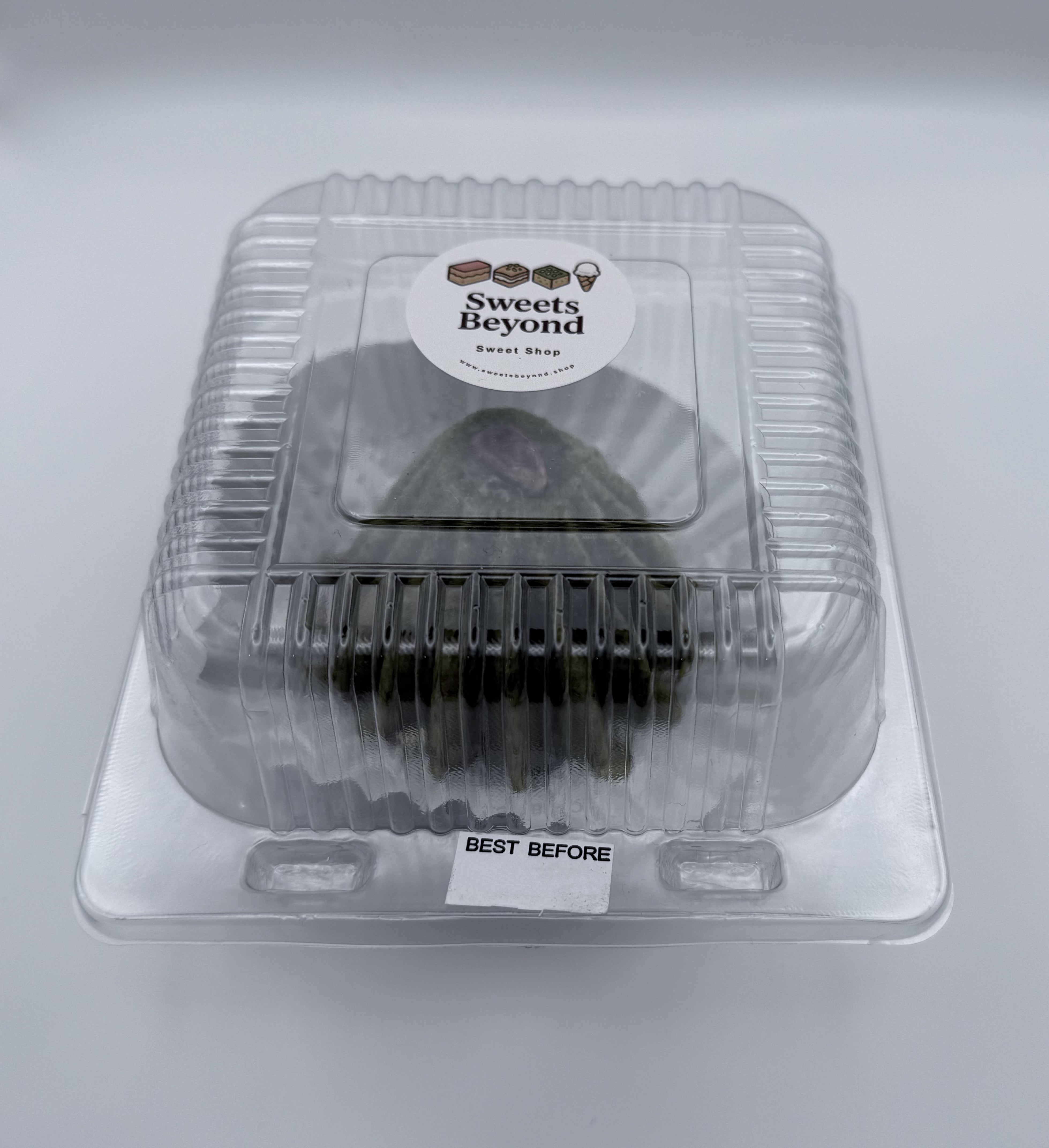 Clear plastic container with pistachio velvet treat inside, labeled 'Sweets Beyond' Shop, on a white background.